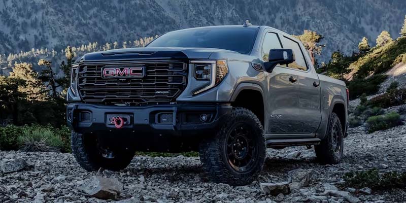 A 2023 GMC Sierra 1500 parked on a rocky mountain landscape, showcasing its rugged design against a natural backdrop.