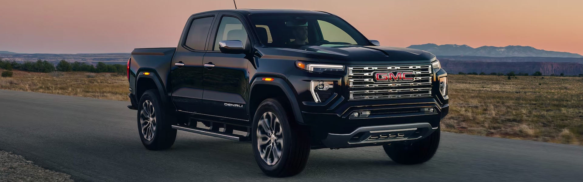 Black GMC Canyon pickup truck driving on a scenic road.