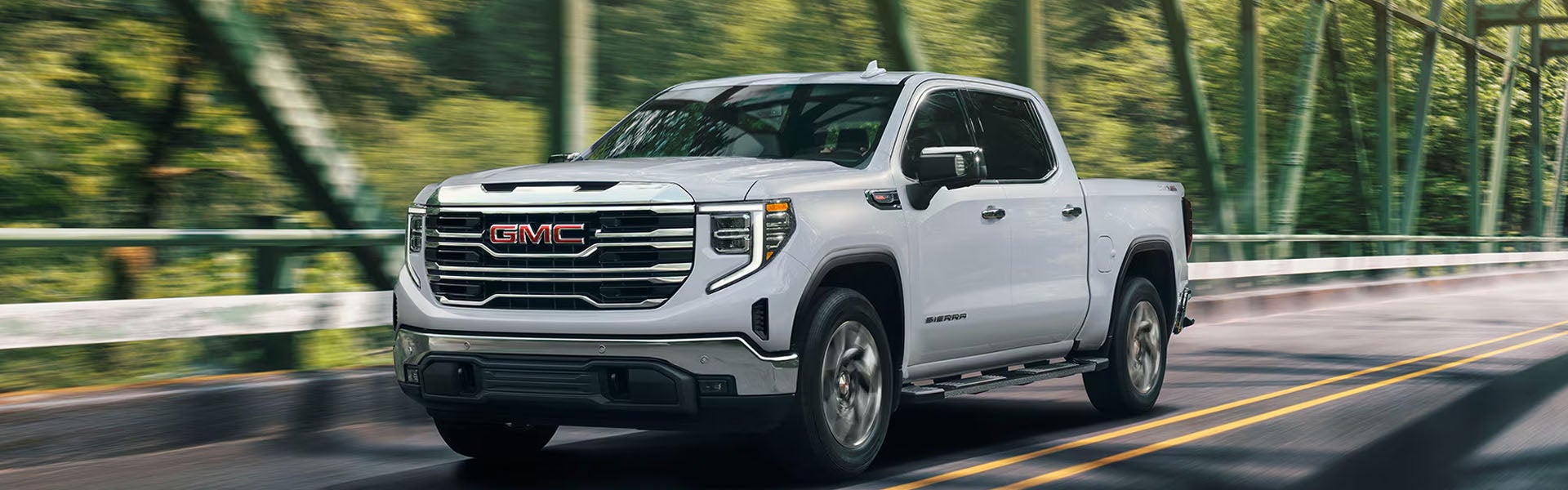 GMC Sierra pickup truck driving on a scenic road.