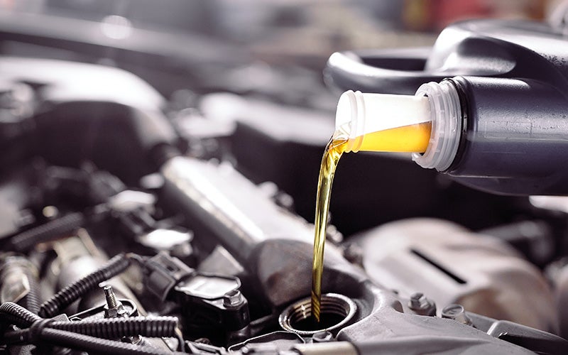 A person pouring oil into a car engine, ensuring proper maintenance and lubrication for optimal vehicle performance.